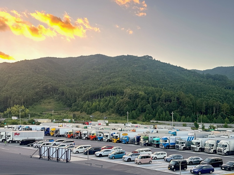 夕焼けの空と、山にかこまれた広い駐車場の写真